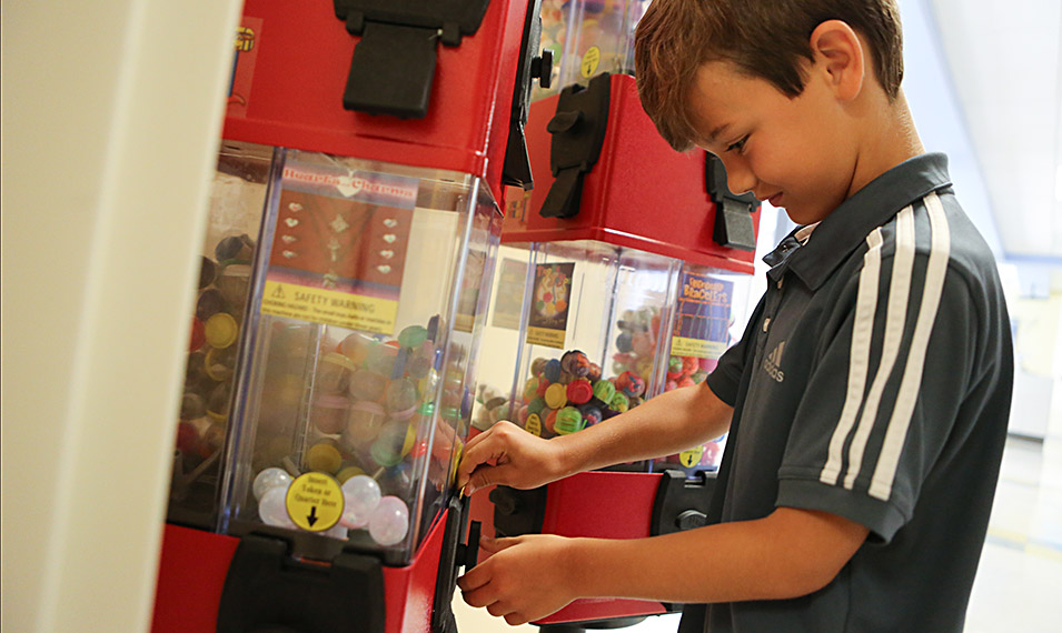 Little boy putting a quarter in a gum ball machine